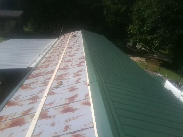 Old rusted panels beside newly installed green metal roofing — Wind Damage Roof Repair by Roofing Brothers in London