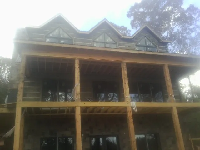 Dormers and porch framing on a large log home under construction — Roof Coating work by our crew in London